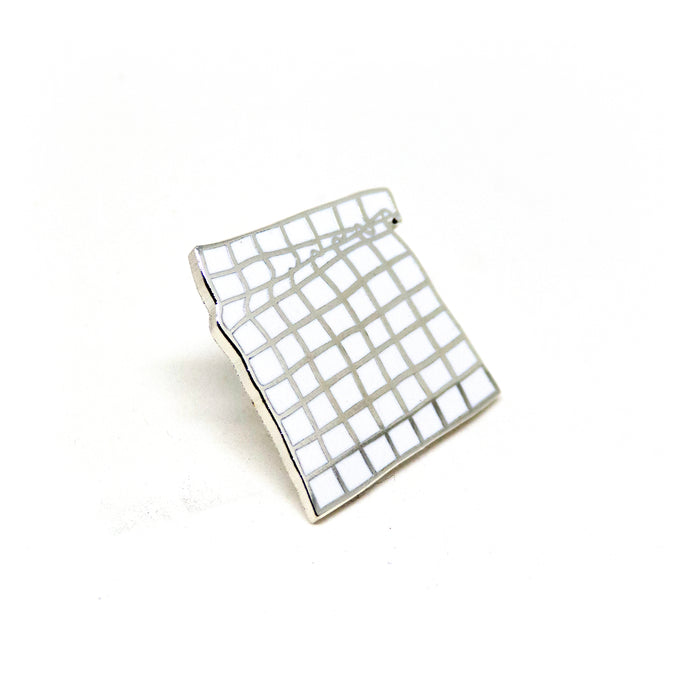 hard enamel pin, a 9x7 grid of squares curling folding near the top like cloth, silver outlines on white background