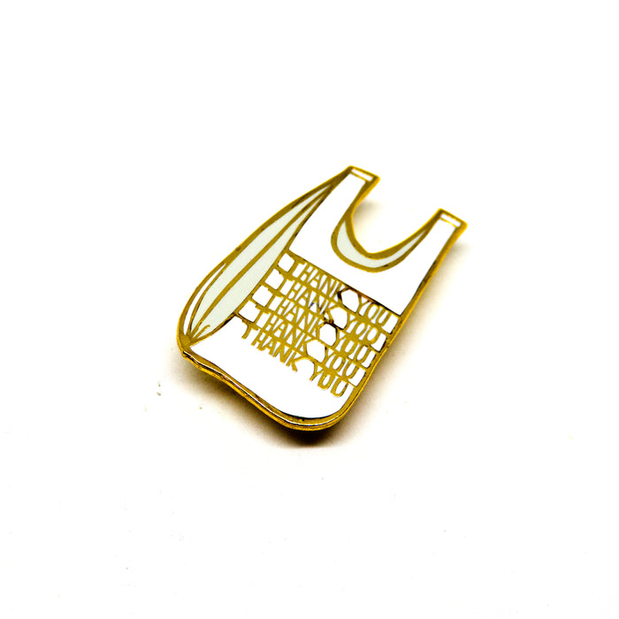hard enamel pin, plastic grocery bag with the words "Thank You" repeated vertically on it five times, gold outlines, white bag, light grey shadows